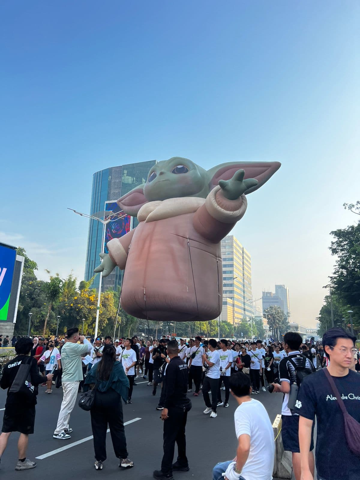 Large helium inflatable of Grogu floating above a street parade crowd, built for Disney Indonesia