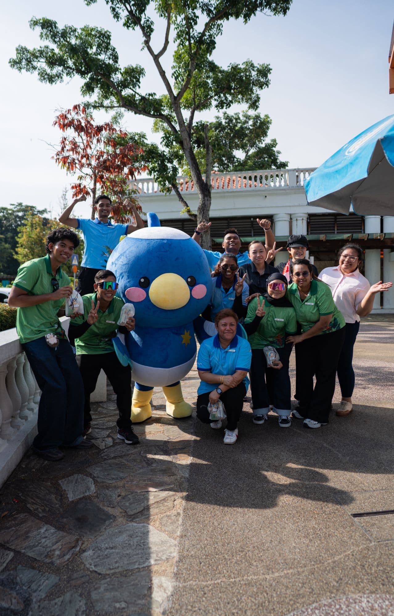 A blue bird mascot posing with event crew outdoors