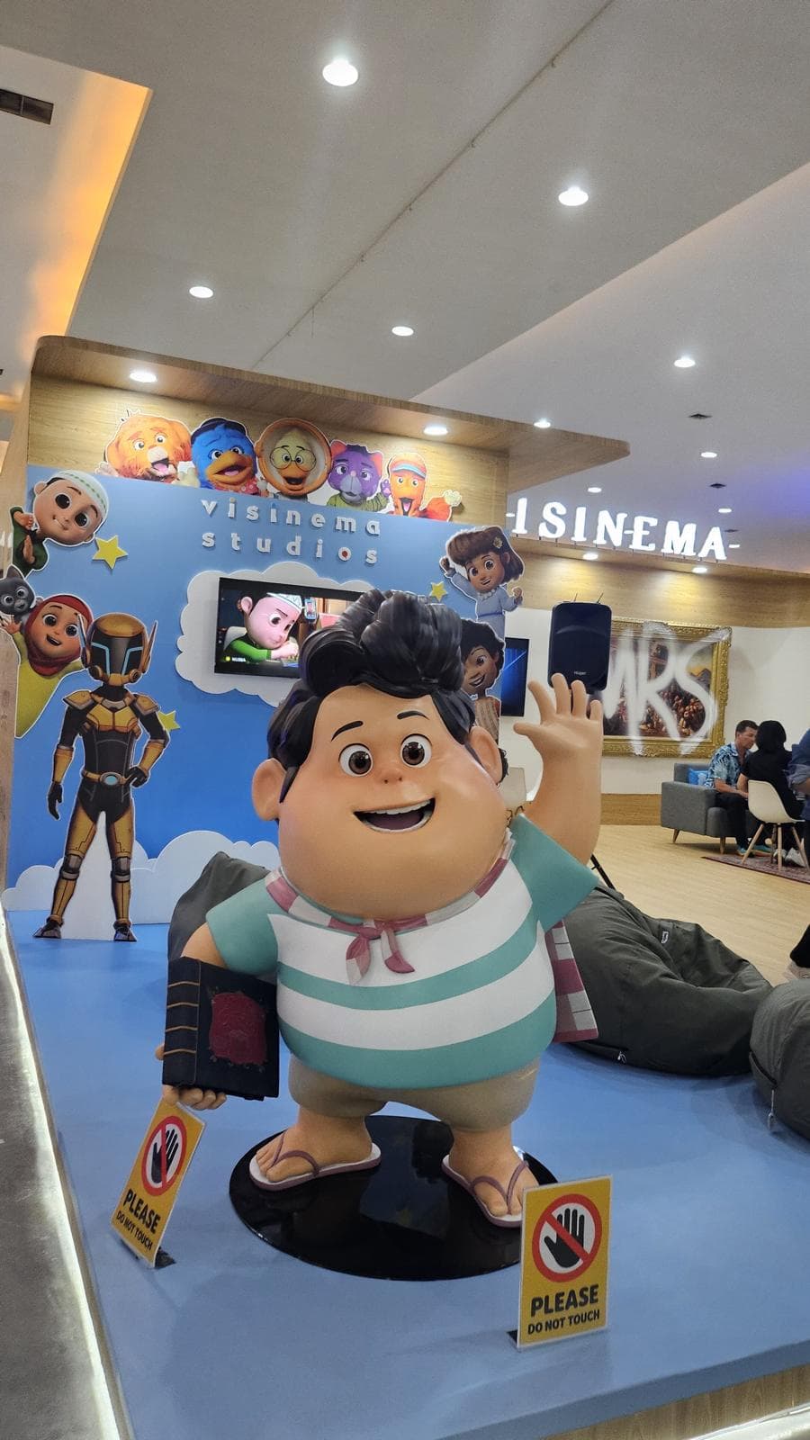 Statue of Don from the animated film Jumbo, built for Visinema Studios, waving and holding a book at the studio exhibition stand